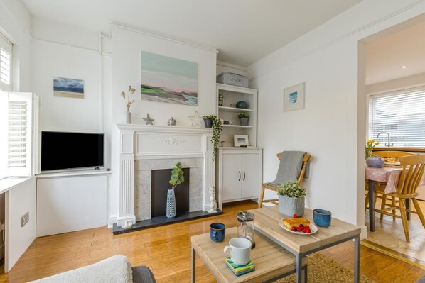 A living room with a fireplace, a television, and a dining area with a table set for two.