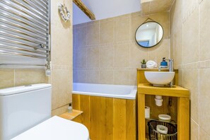 A bathroom with a bathtub, a wooden vanity with a sink, and a toilet.
