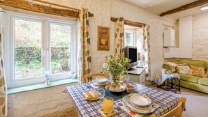 Una habitación rústica con una mesa de comedor dispuesta para el desayuno, un televisor y un sofá verde.