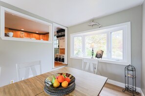 Spiseplads med et træbord, en skål med frugt og et vindue med udsigt til det fri.