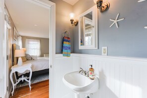 Une chambre à coucher avec un lit, une table de chevet, une lampe et une vue sur la salle de bain.