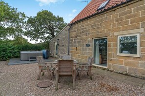 A stone building with a tiled roof, a patio with a table and chairs, and a hot tub. - 2 Bed in Fylingdales (oc-wa313) (Fylingdales)