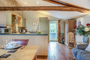 A cozy kitchen with wooden beams, a dining area with a table set for two, and a view through a door to a balcony. - 2 Bed in Fylingdales (oc-wa313) (Fylingdales)