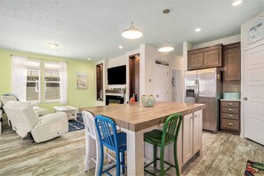 A modern kitchen with a wooden island, bar stools, a flat-screen TV, and stainless steel appliances. - Welcome to Slice of Haven with HOT TUB! (South Haven)