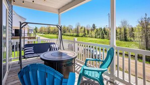Una terrazza coperta all'aperto con barbecue, sedie e vista su un paesaggio verde.