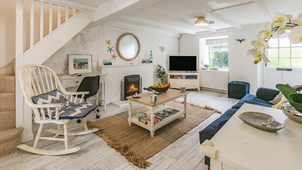 Een woonkamer met een open haard, een televisie, een eettafel en een trap.