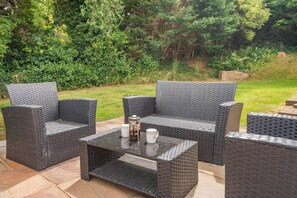 Une terrasse extérieure avec des meubles en osier et une table en verre.