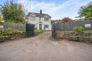 A private driveway leading to a two-story house with a stone wall and a wooden fence.