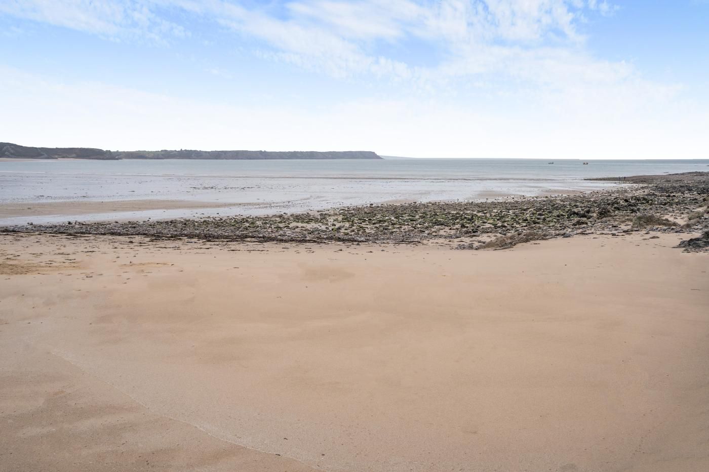 Una playa con arena y afloramientos rocosos.