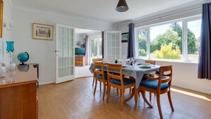 A dining area with a table set for four, wooden chairs, a globe, and a framed picture on the wall.
