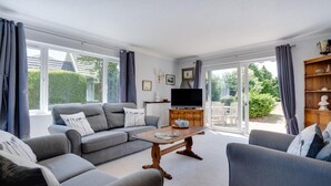 A modern living room with a grey sofa set, a wooden coffee table, and a television.
