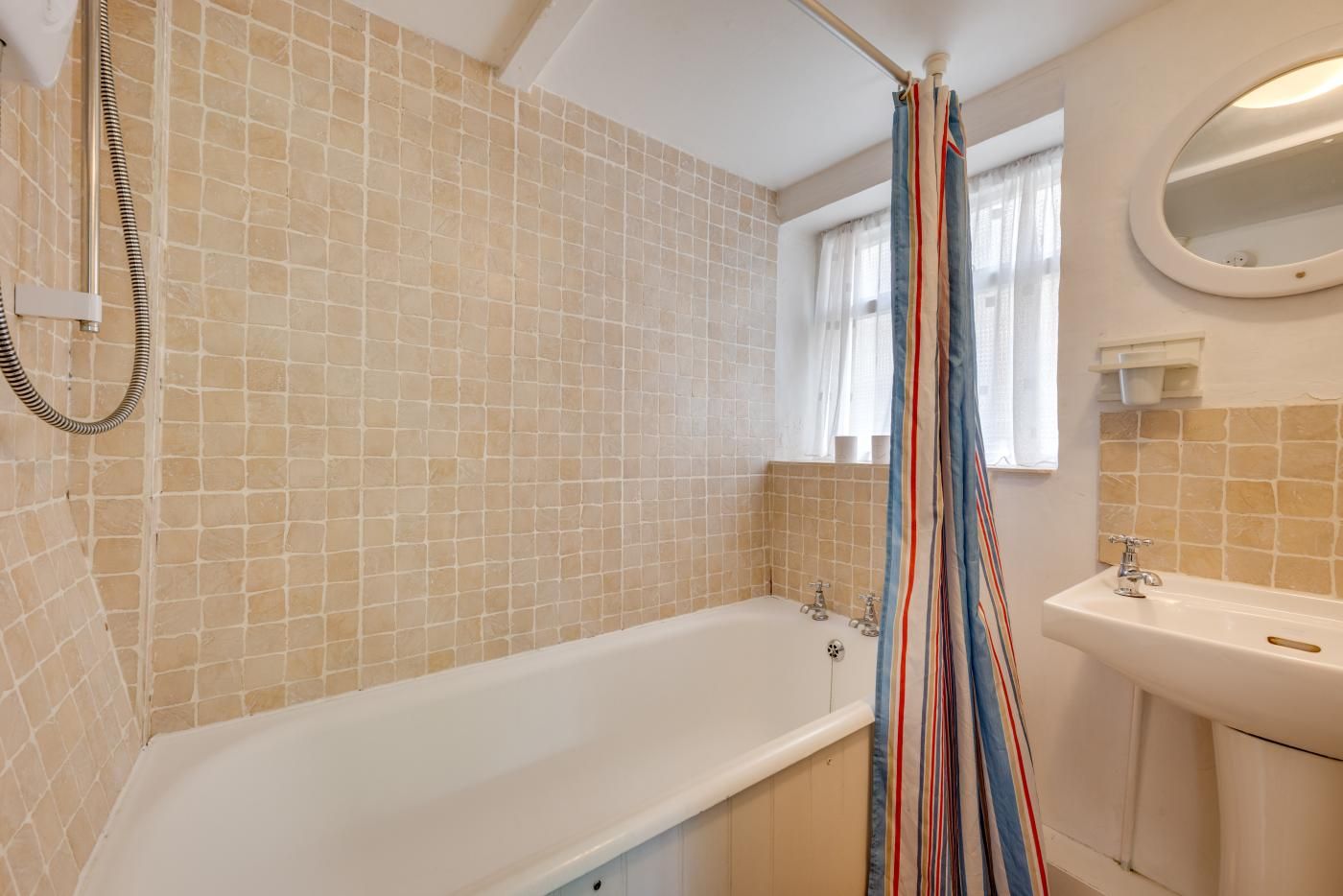 A bathroom with a bathtub, a shower curtain, and a sink.
