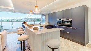A modern kitchen with a central island, dark cabinets, and pendant lighting. - 10 Bed in Shanklin (oc-t33547) (Shanklin)