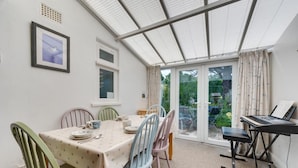 A conservatory with a dining table, chairs, and a piano. - 2 Bed in Westleton (oc-gors) (Westleton)