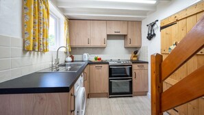 A kitchen with wooden cabinets, a black countertop, a sink, a stove, and an oven. - 2 Bed in Westleton (oc-gors) (Westleton)
