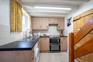 Eine Küche mit Holzausstattung, einer schwarzen Arbeitsplatte, einem Spülbecken, einem Herd und einem Backofen.