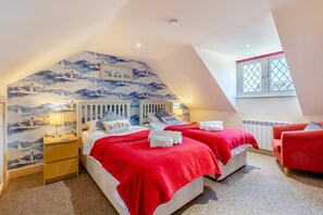 A bedroom with two beds, a red chair, a window with a view, and a mural on the wall. - 2 Bed in Weybourne (oc-1789) (Weybourne)