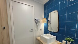 A bathroom with a white door, a sink with a mirror, and blue tiles on the wall. - Sea View • 3 King Beds • Premium Comfort in BC (Balneário Camboriú)