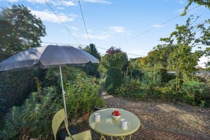 An outdoor seating area with a table, chairs, and a large umbrella. - 1 Bed in Stanhoe (oc-1792) (Stanhoe)