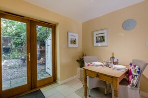 A dining area with a table set for two, a clock on the wall, and framed pictures above the table. - 1 Bed in Stanhoe (oc-1792) (Stanhoe)