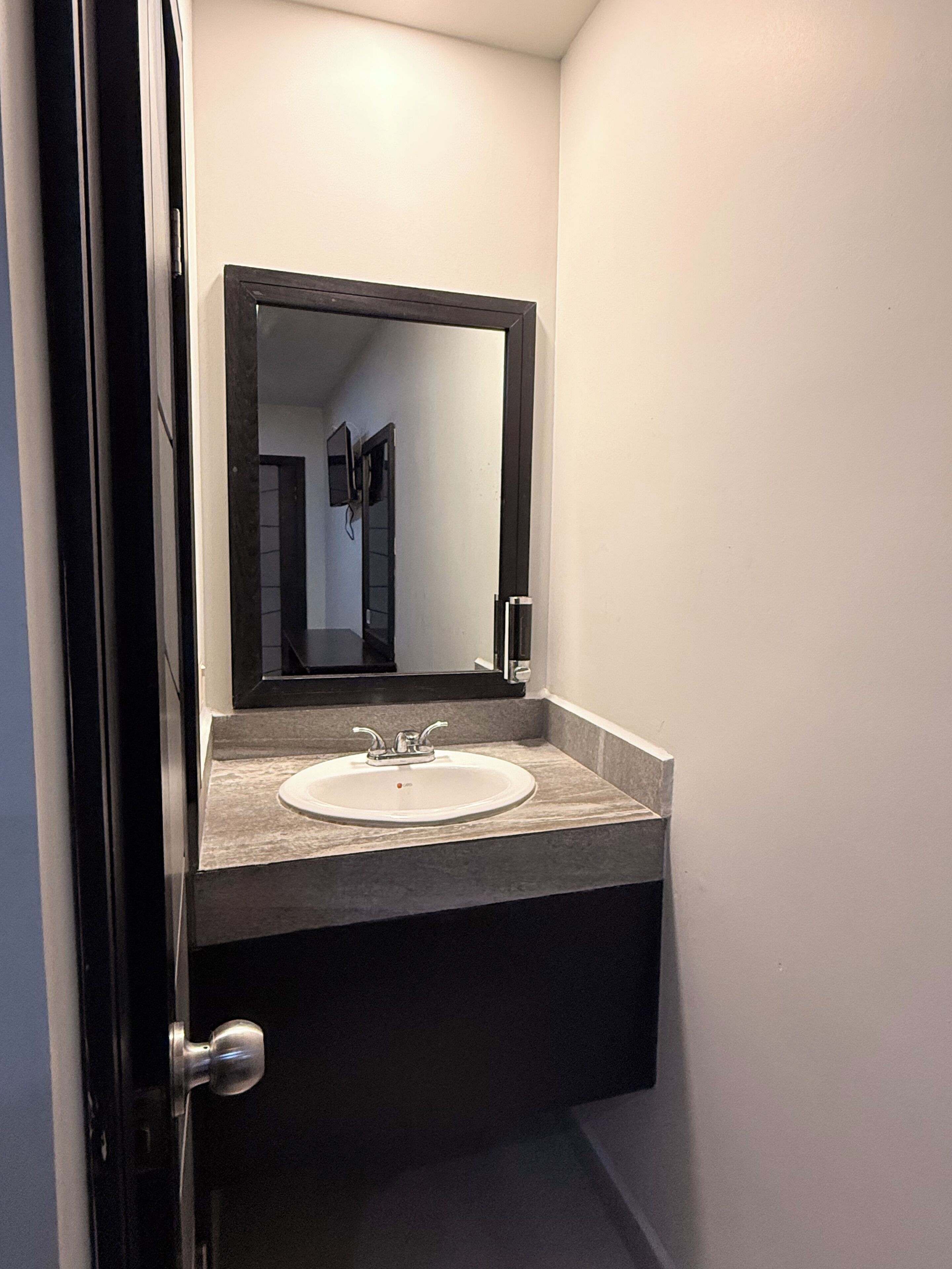 A bathroom with a white sink, a mirror above it, and a door to the left.