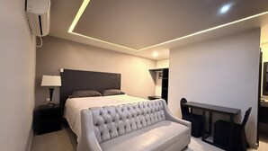 Um quarto moderno com uma cama grande, um sofá cinzento, uma escrivaninha e um guarda-roupa.