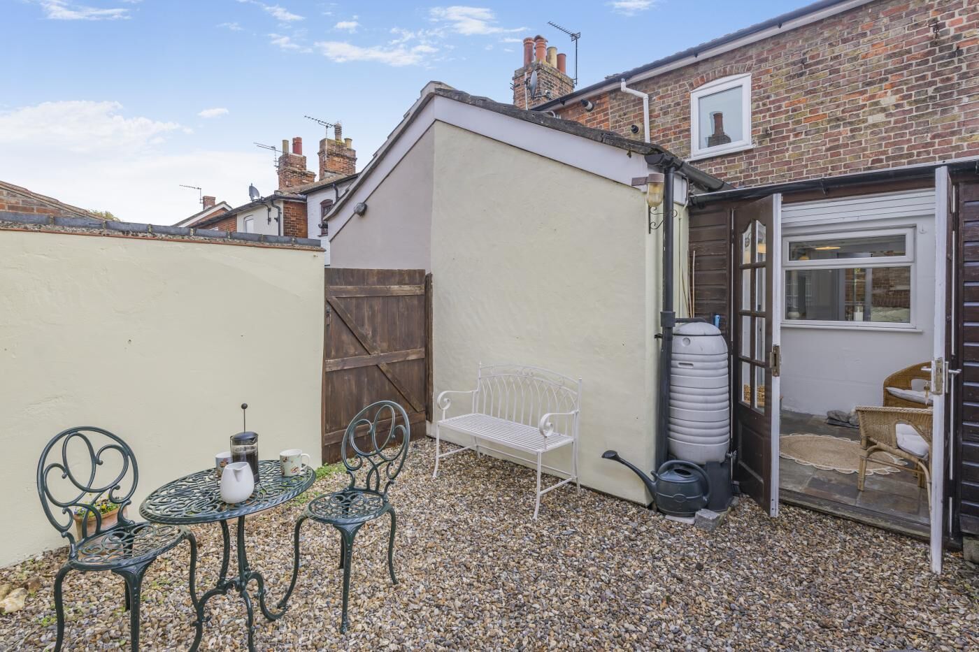 A patio area with a table and chairs, a bench, a water tank, and a shed.