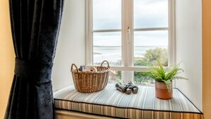 Ikkunalaudalla on rottinkikori, kiikarit ja ruukussa oleva kasvi.