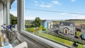 A view from a window overlooking a coastal area with houses, a tree, and a clear sky. - 2 Bed in Penally (oc-pw9077) (Penally)