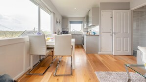 A modern kitchen with a dining area, large windows, and a view of the countryside. - 2 Bed in Penally (oc-pw9077) (Penally)