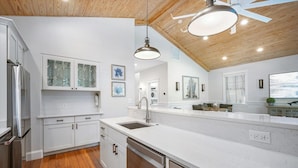 A modern kitchen with white cabinetry, a stainless steel dishwasher, and a wooden ceiling. - Spacious Beachfront Home in Holmes Beach on Anna Maria Island! Swell Life (Holmes Beach)