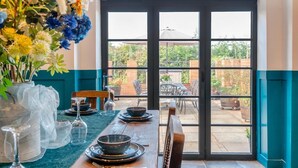 Un comedor con una mesa dispuesta para cuatro personas, un ventanal y vistas al patio exterior.