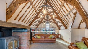 Un loft acogedor con vigas de madera a la vista, una chimenea, un sofá de cuero y una estantería.