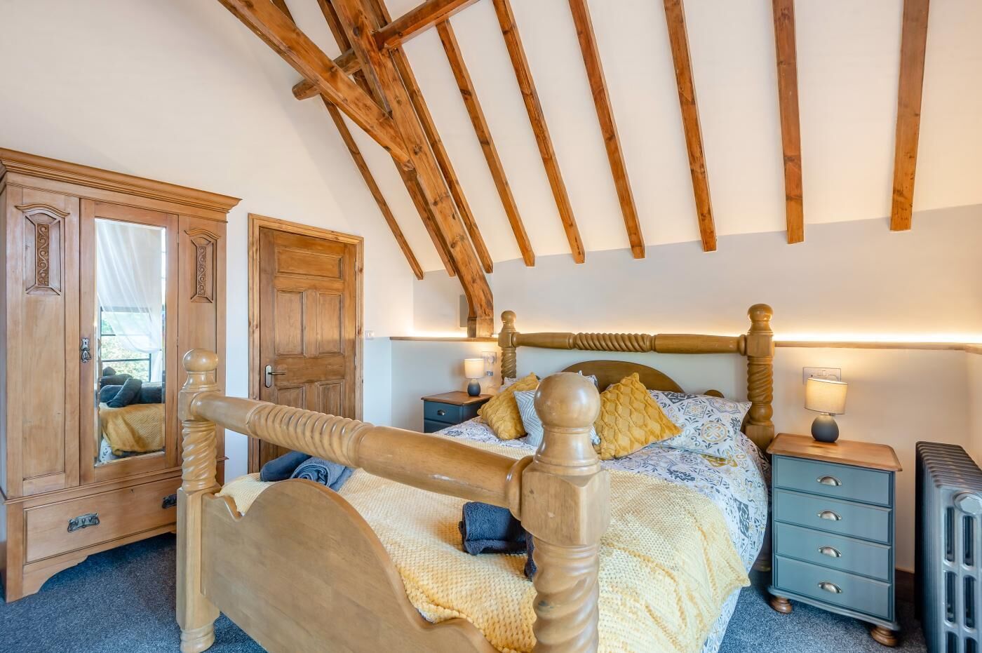Une chambre à coucher avec un lit en bois, une table de chevet, une commode et un miroir.