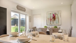 Un coin repas doté d’un comptoir en marbre, de chaises blanches et d’une table à manger dressée pour quatre personnes.