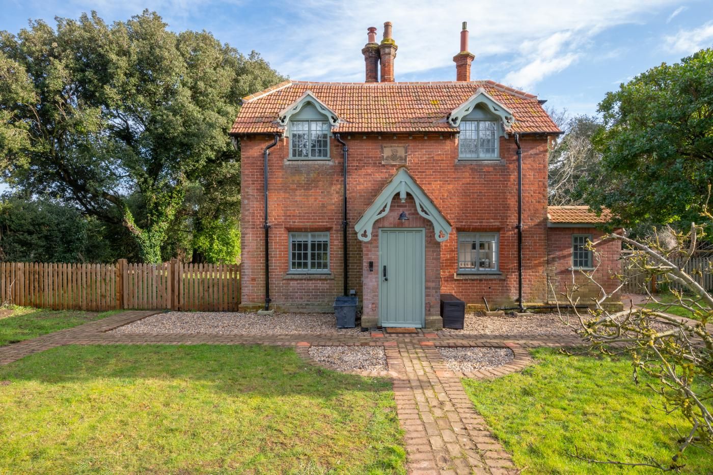 A brick house with a tiled roof, a front door, and a small front garden.