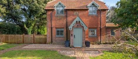 A brick house with a tiled roof, a front door, and a small front garden.
