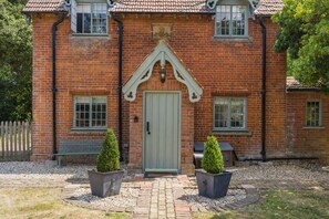 A brick house with a green door, two potted plants, and a white picket fence. - 2 Bed in Wells-next-the-Sea (oc-2229) (Wighton)