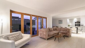 A modern living room with a white sofa, a beige sectional, and a coffee table. There is a sliding glass door leading to an outdoor area. - 4 Bed in Saundersfoot (oc-493314) (Saundersfoot)