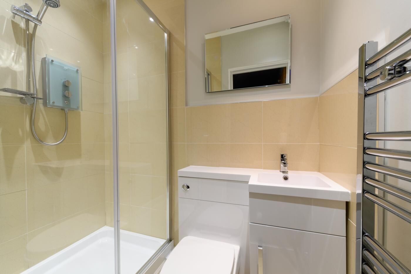 A modern bathroom with a glass shower enclosure, a white sink, and a mirror above it.