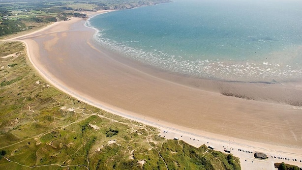 An aerial view of a coastal beach with a long stretch of sand, a clear blue sea, and a hilly landscape in the background. - 1 Bed in Langland (oc-hh1423) (Newton)