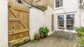 Een houten terras met potplanten, een opklapbare tafel en stoelen.