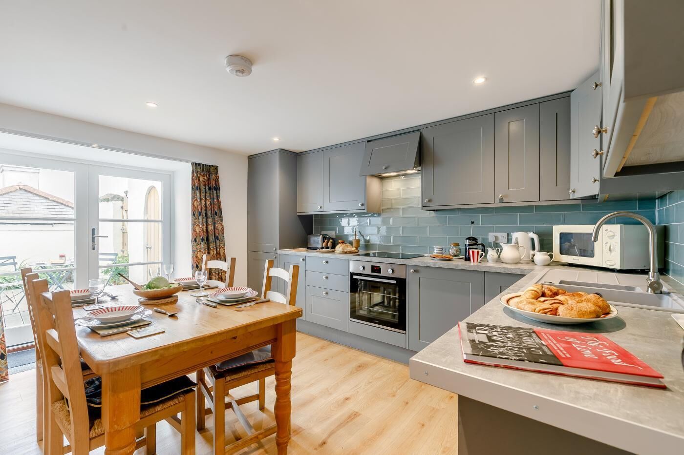 A modern kitchen with grey cabinets, a built-in oven, and a microwave.