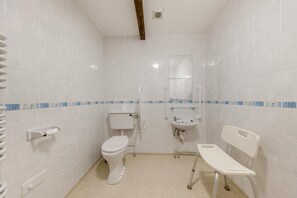 Ein kleines, weißes Badezimmer mit Toilette, Waschbecken und Spiegel.