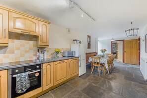 Eine Küche mit Holzausstattung, einem eingebauten Ofen und einer Essecke mit Tisch und Stühlen.