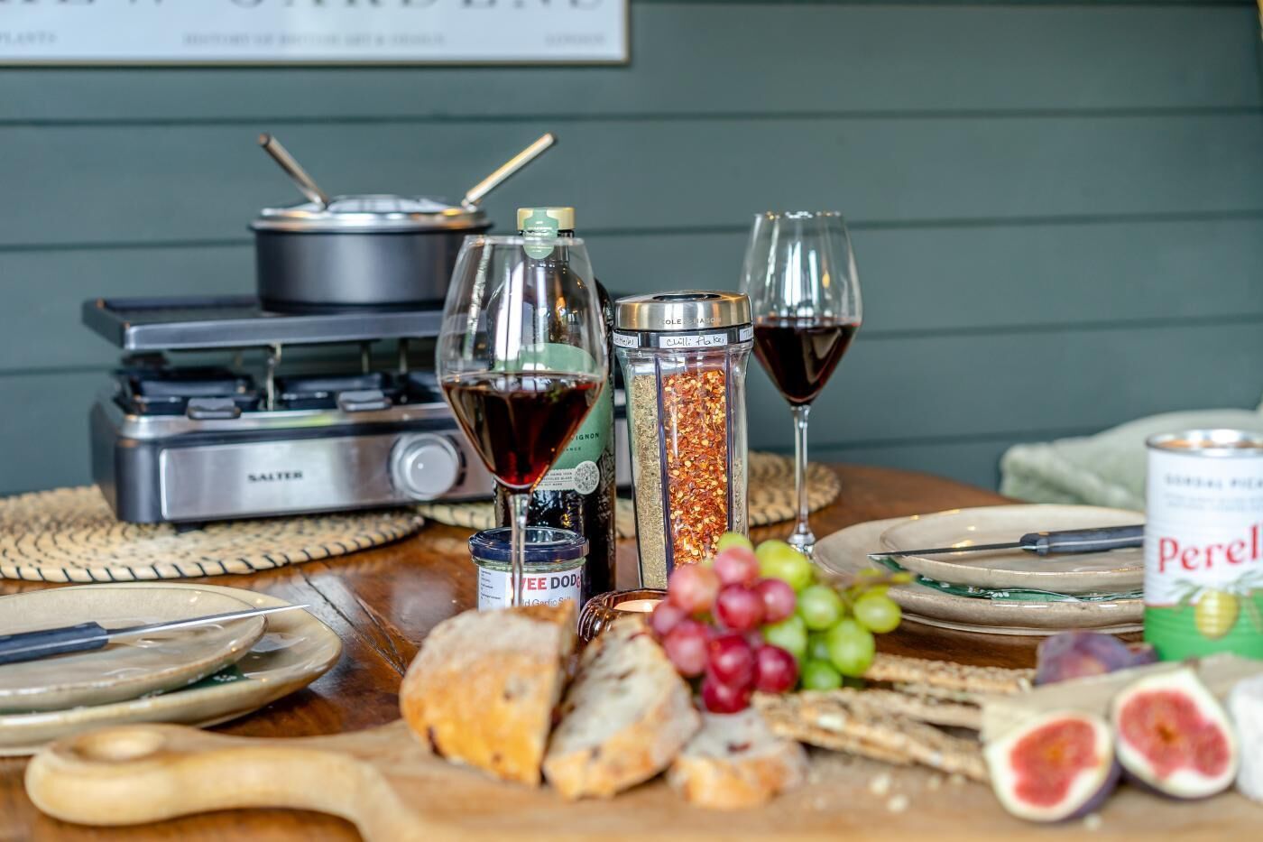 A table with food items, wine glasses, and a portable stove.
