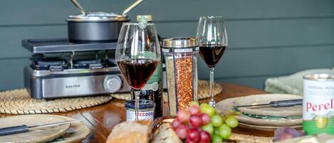 A table with food items, wine glasses, and a portable stove.