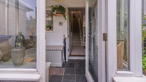 A modern home entrance with a glass door, a staircase leading to the upper floor, and a small bench with a basket of plants. - 2 Bed in Ladybank (oc-n33092) (Letham)