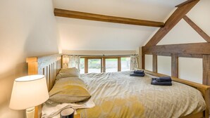 Ein Schlafzimmer mit einem Bett, einer Lampe und Blick durch ein Fenster.