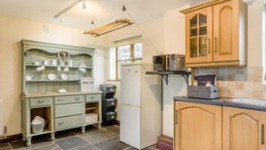 Eine Küche mit einem grünen Schrank, einem weißen Kühlschrank, Holzschränken und einer Mikrowelle.